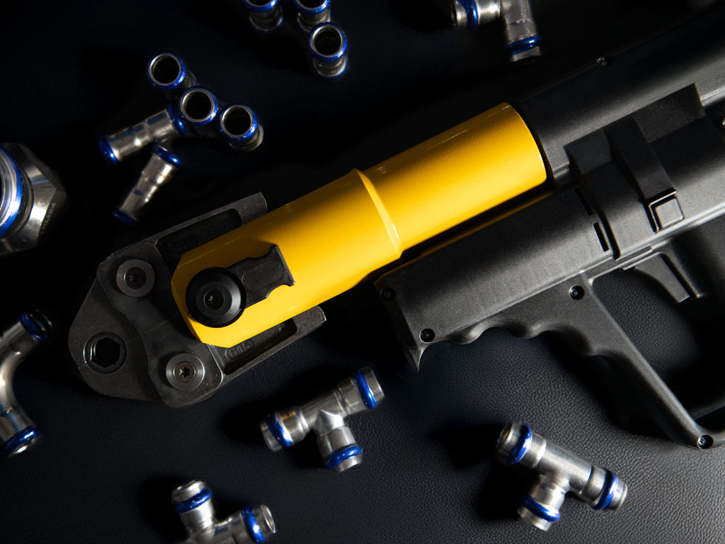 Detailaufnahme einer Presszange mit gelbem Griff und Metallkopf, geeignet zum Verpressen von Pressfittings in Rohrsystemen